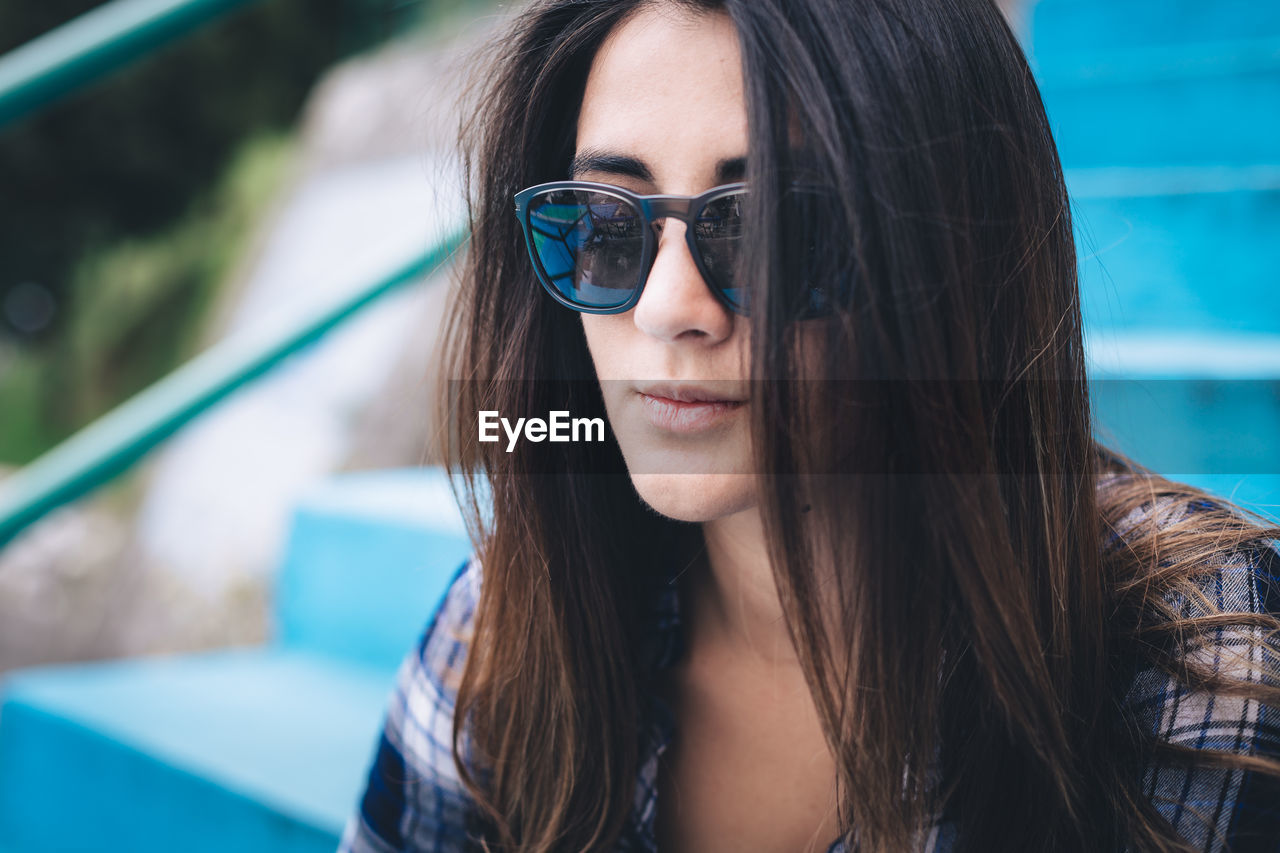 Close-up of young woman wearing sunglasses on steps