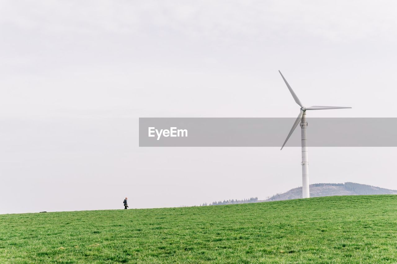 Windmill on grassy field against clear sky