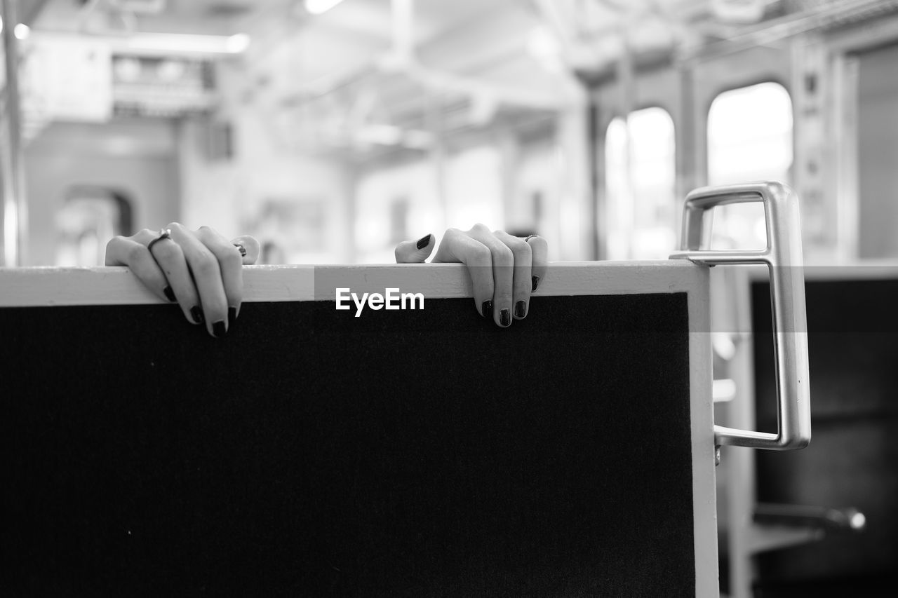 Cropped image of woman holding seat in train