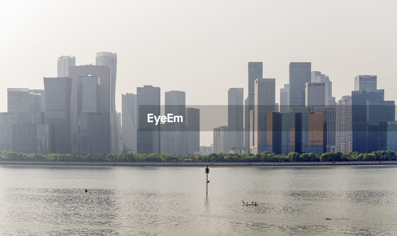 BUILDINGS BY RIVER AGAINST SKY IN CITY