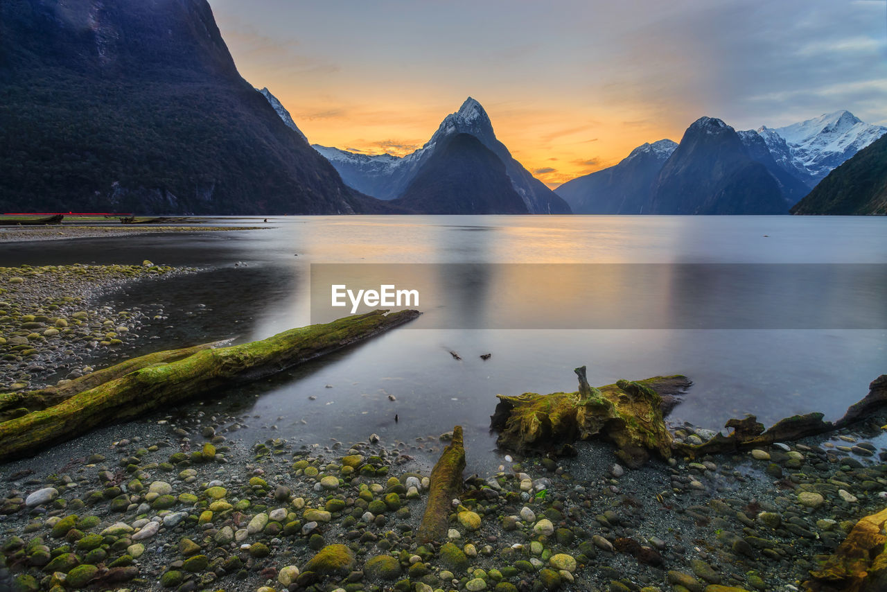 Scenic view of lake and mountains against sky during sunset