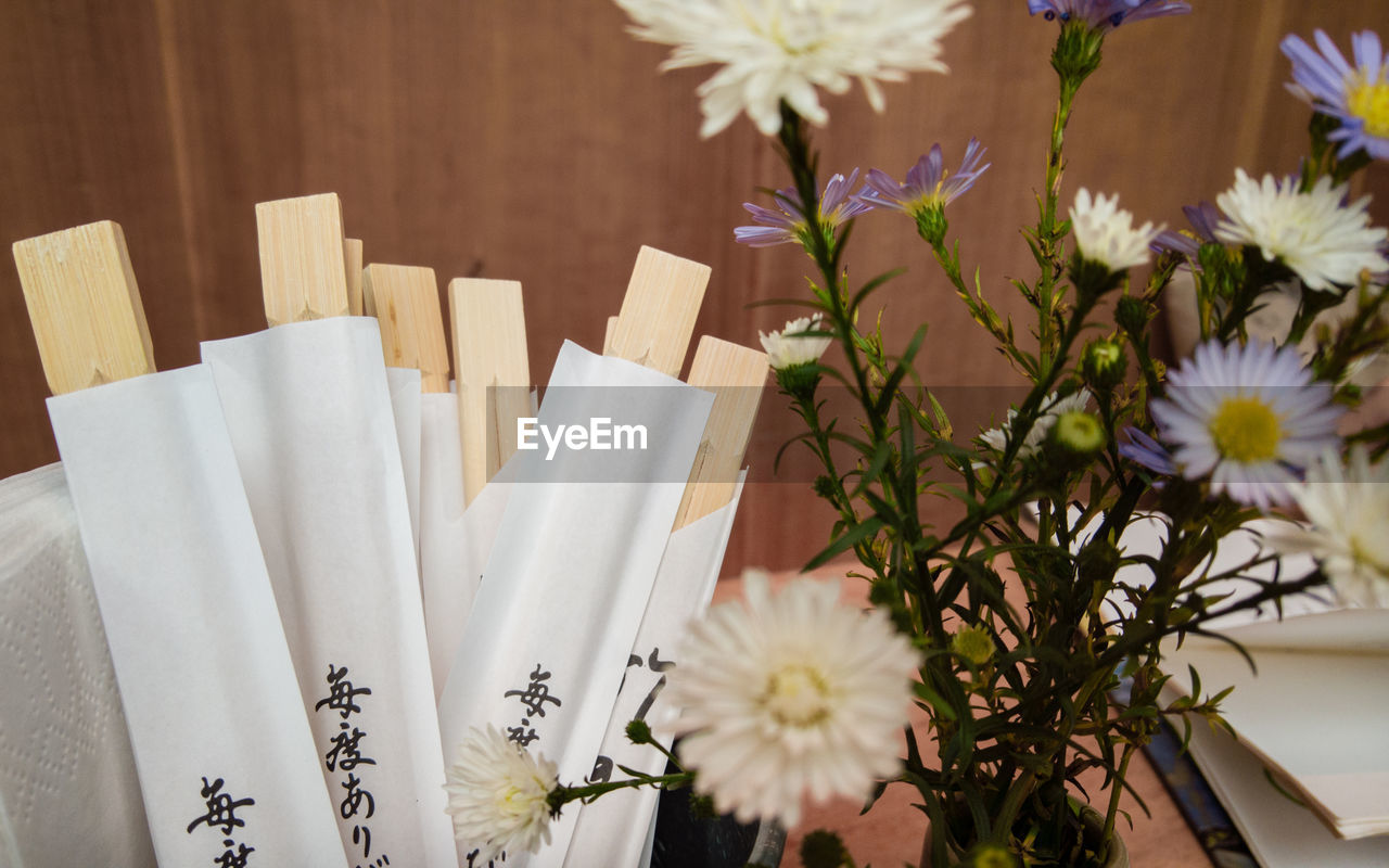 Close-up of flowers by chopsticks in packets on table