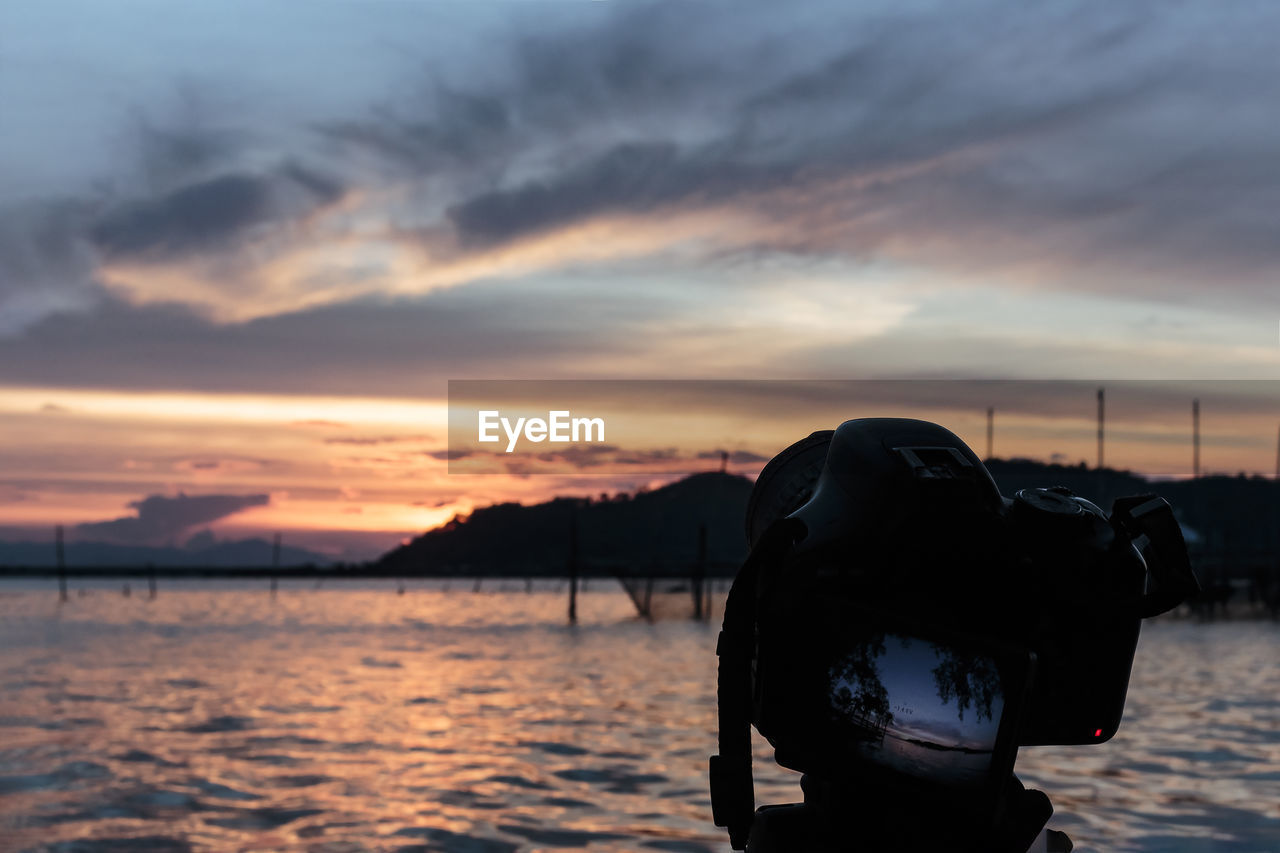 Man photographing sea against sky during sunset