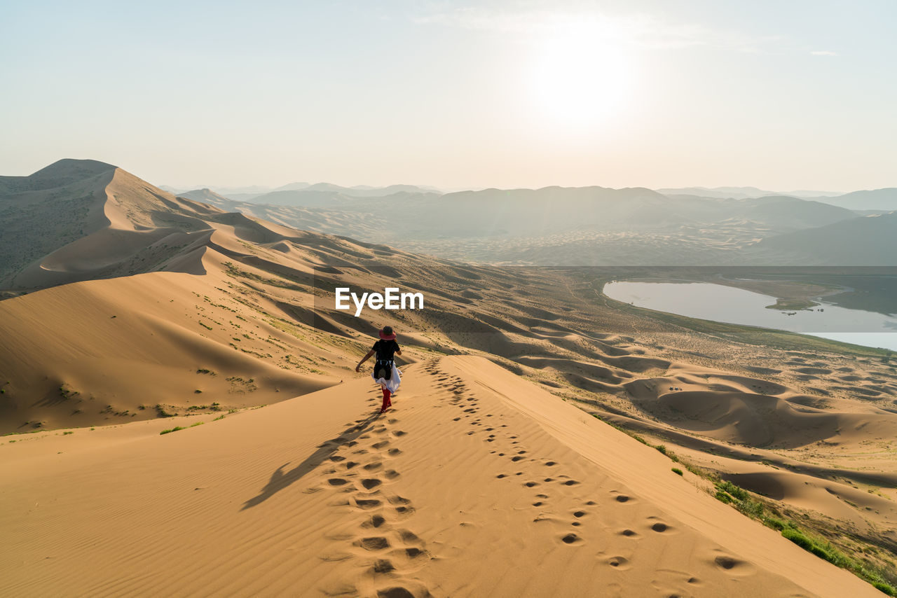 Rear view of woman walking on sand dune in badain jaran desert
