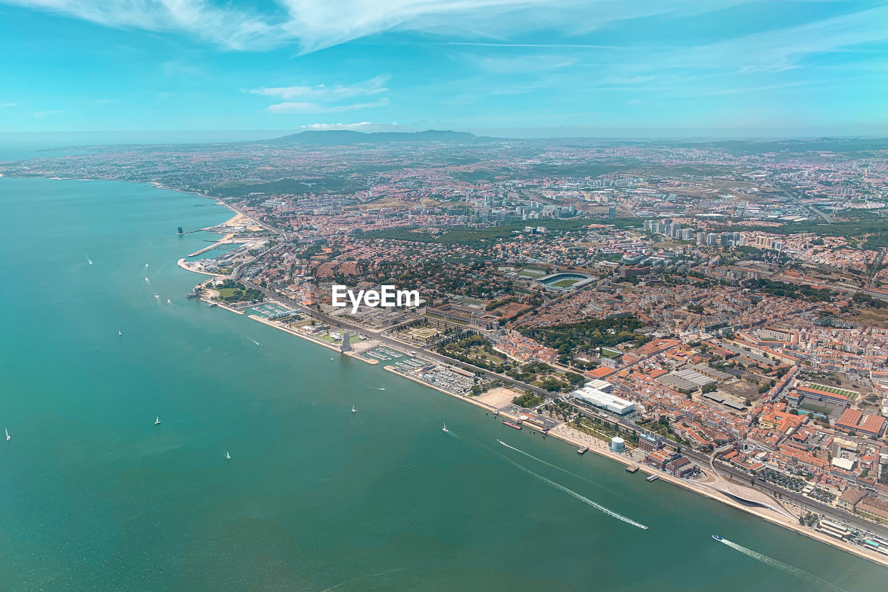 high angle view of cityscape by sea against sky