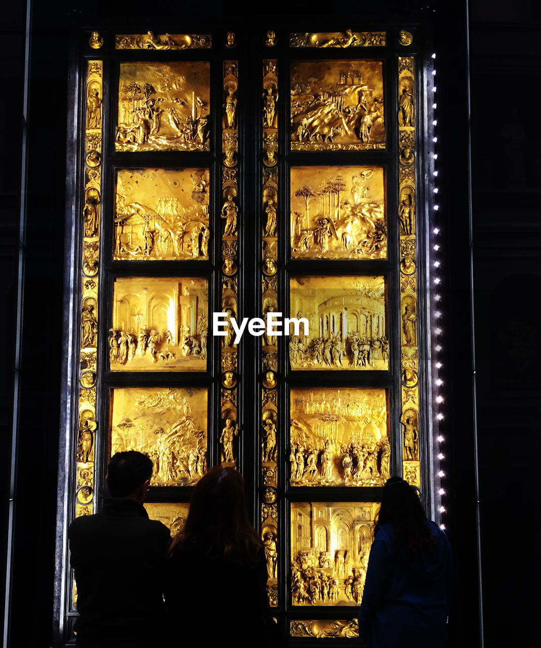 REAR VIEW OF PEOPLE LOOKING THROUGH WINDOW AT HOME