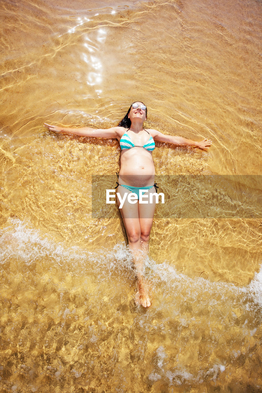 Rear view of woman in bikini standing in water