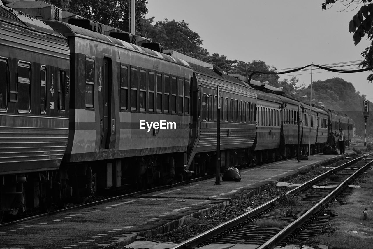 TRAIN AT RAILROAD STATION AGAINST SKY