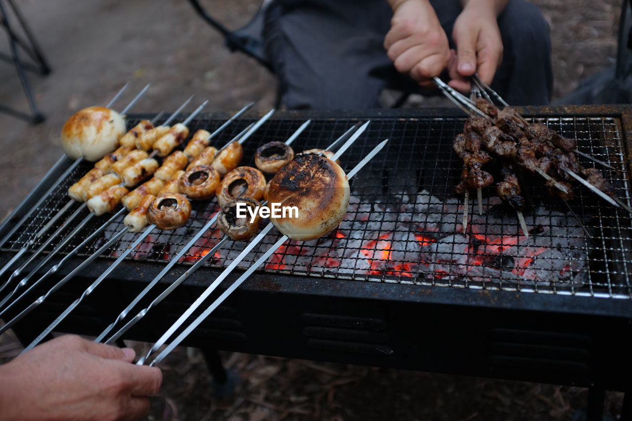 Friends preparing meat on barbecue grill