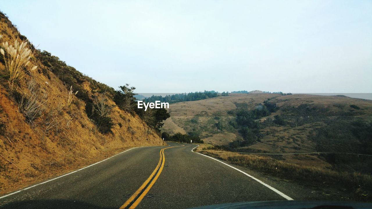 Country road by mountain against sky