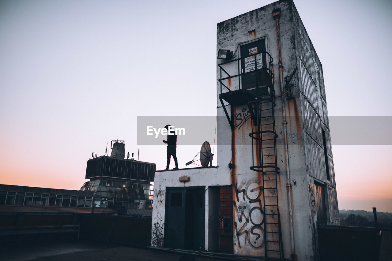 SILHOUETTE OF MAN AGAINST BUILDING