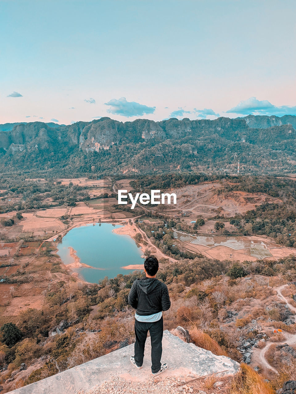 Rear view of man standing on mountain against sky