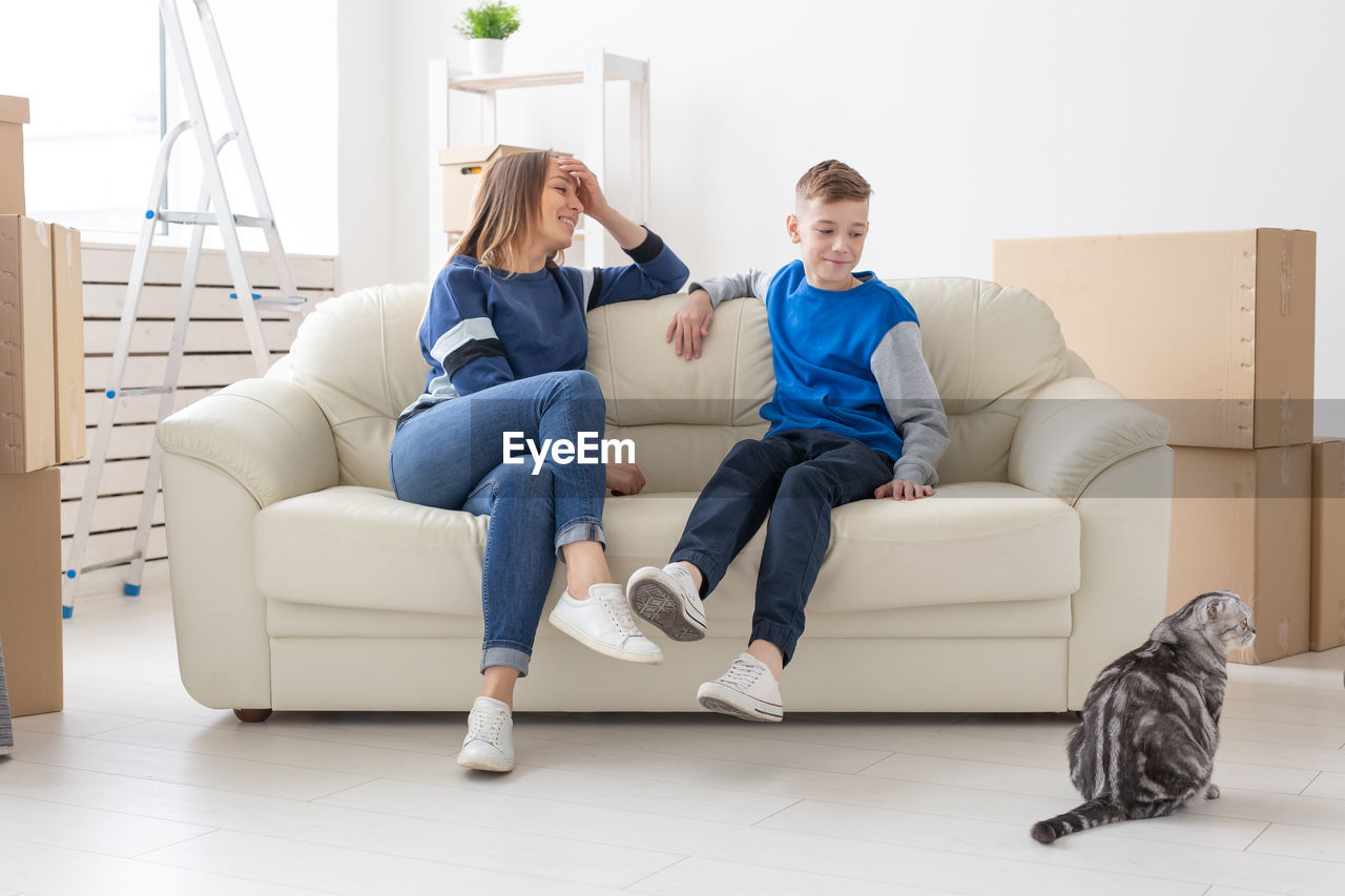 YOUNG WOMAN SITTING ON SOFA AT HOME