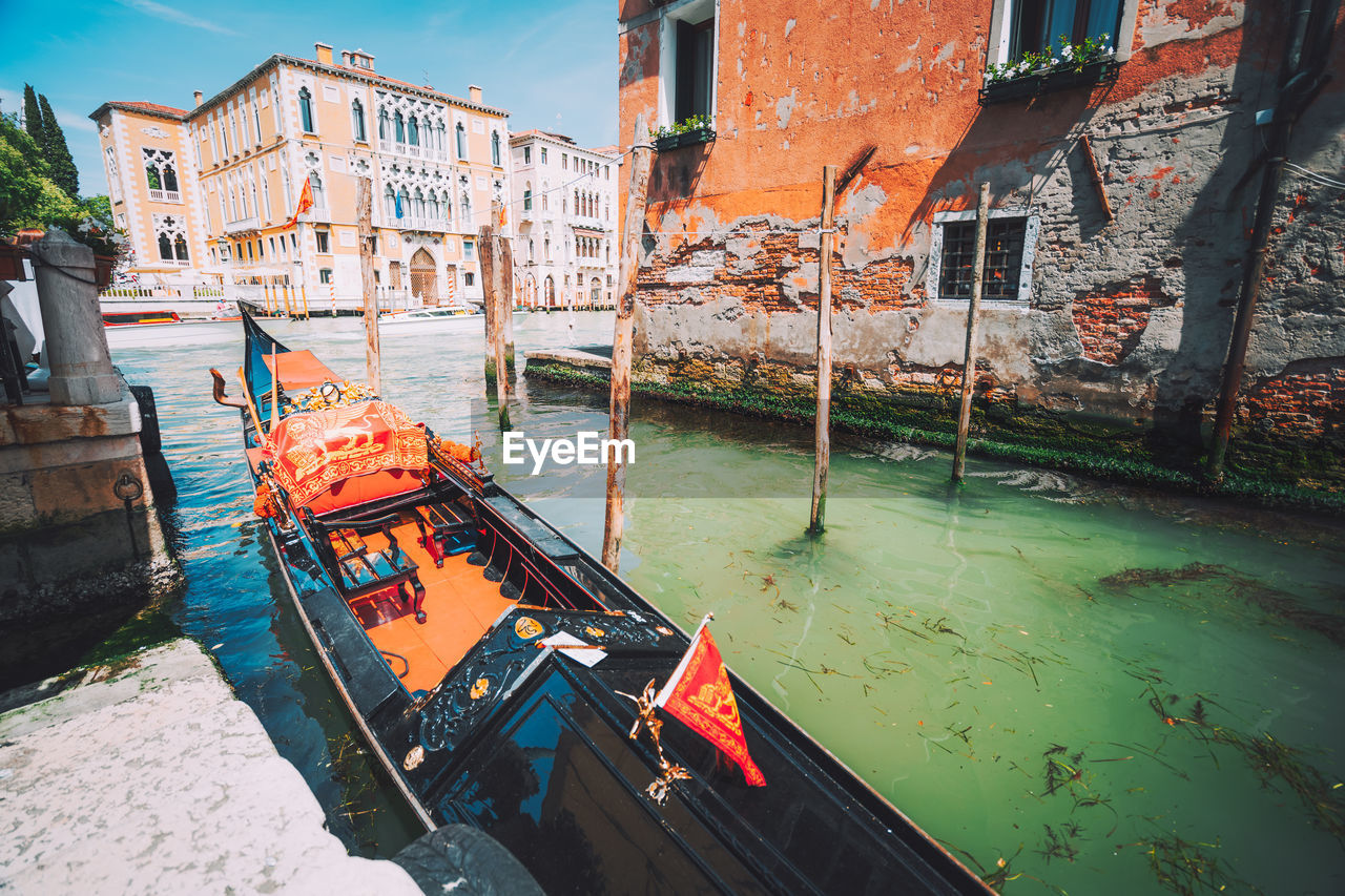 Gondola moored in canal against buildings