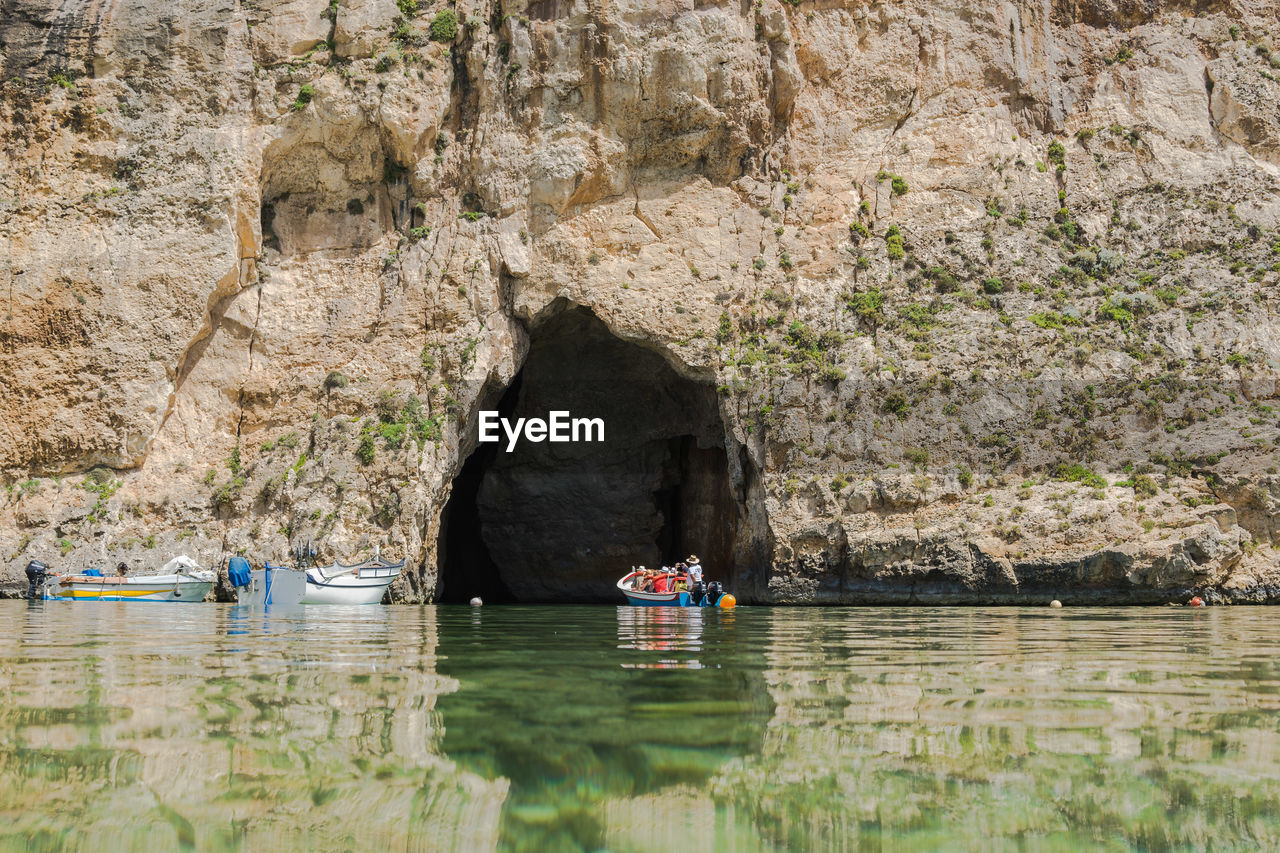 People in boat against rock formation in sea