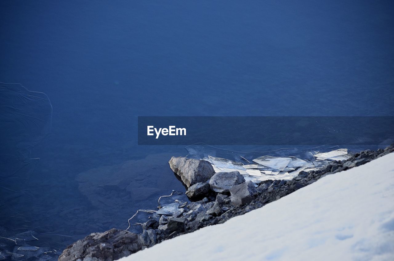 Scenic view of sea by snowcapped mountain against sky