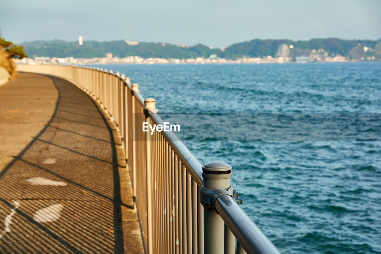 Railing over sea against sky