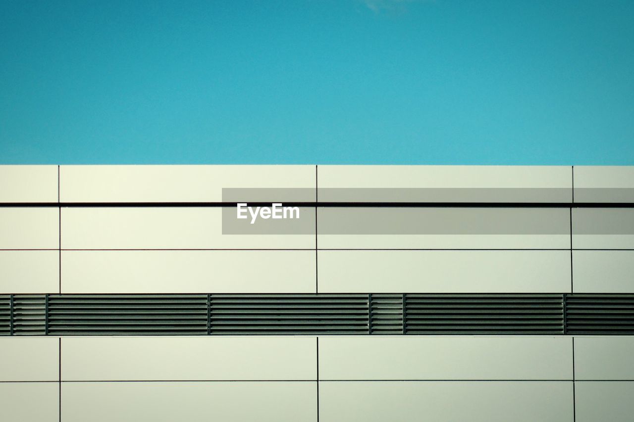 LOW ANGLE VIEW OF MODERN BUILDING AGAINST CLEAR BLUE SKY