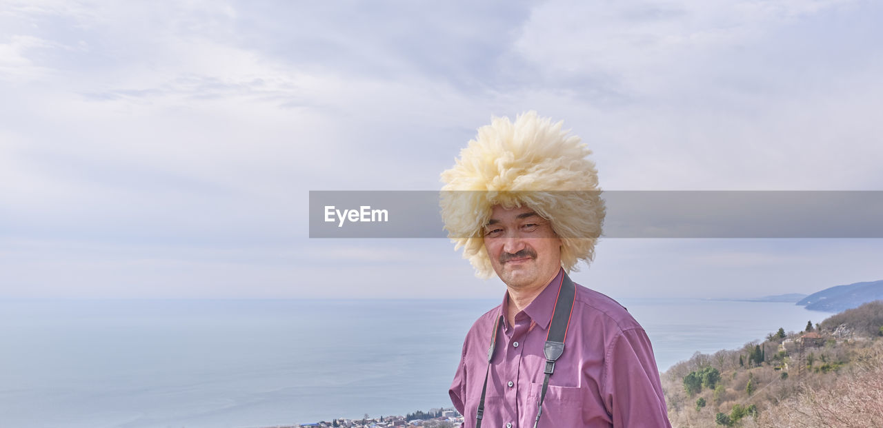 PORTRAIT OF HAPPY WOMAN AGAINST SEA