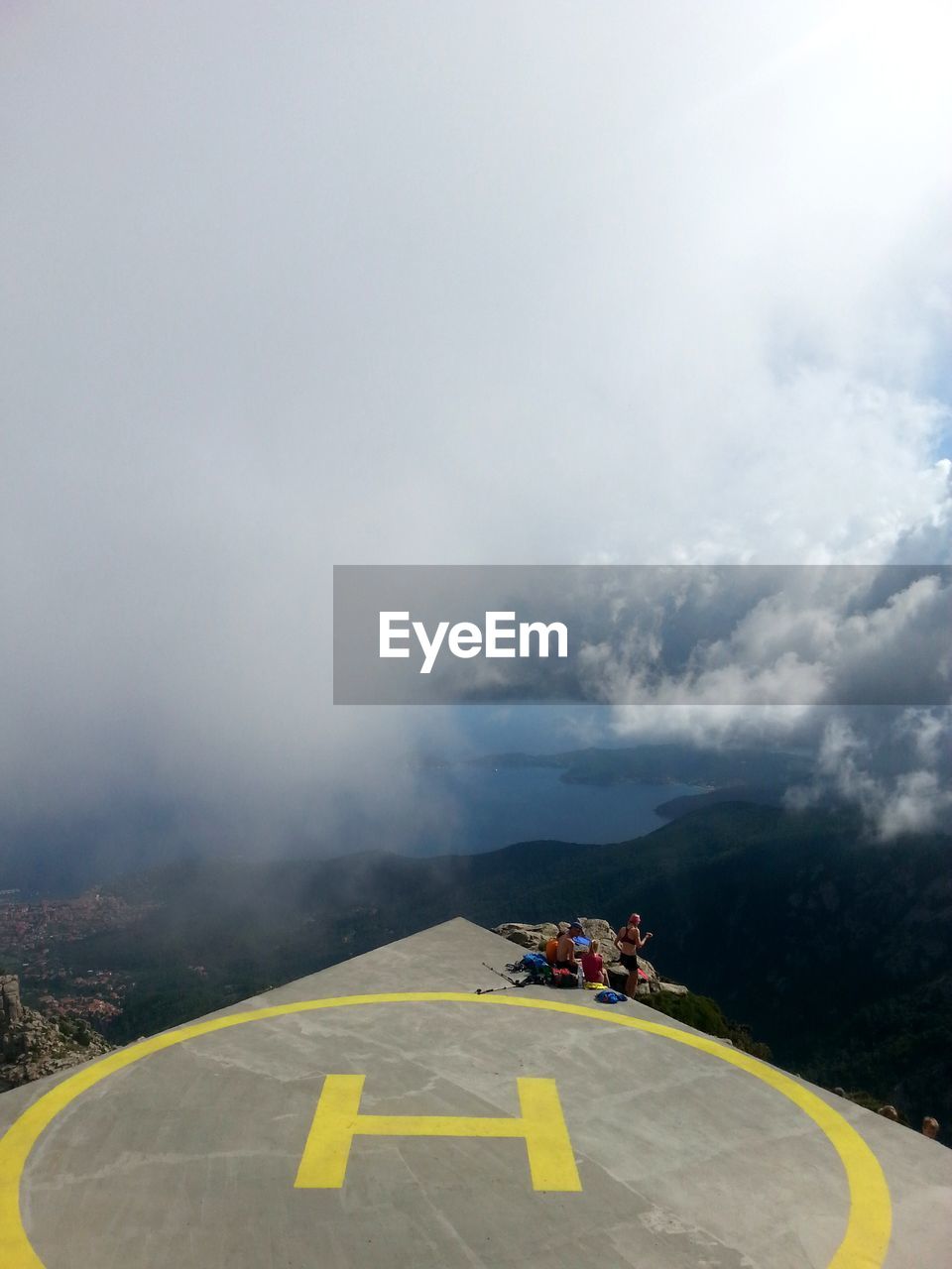 High angle view of friends at helipad on mountain during foggy weather