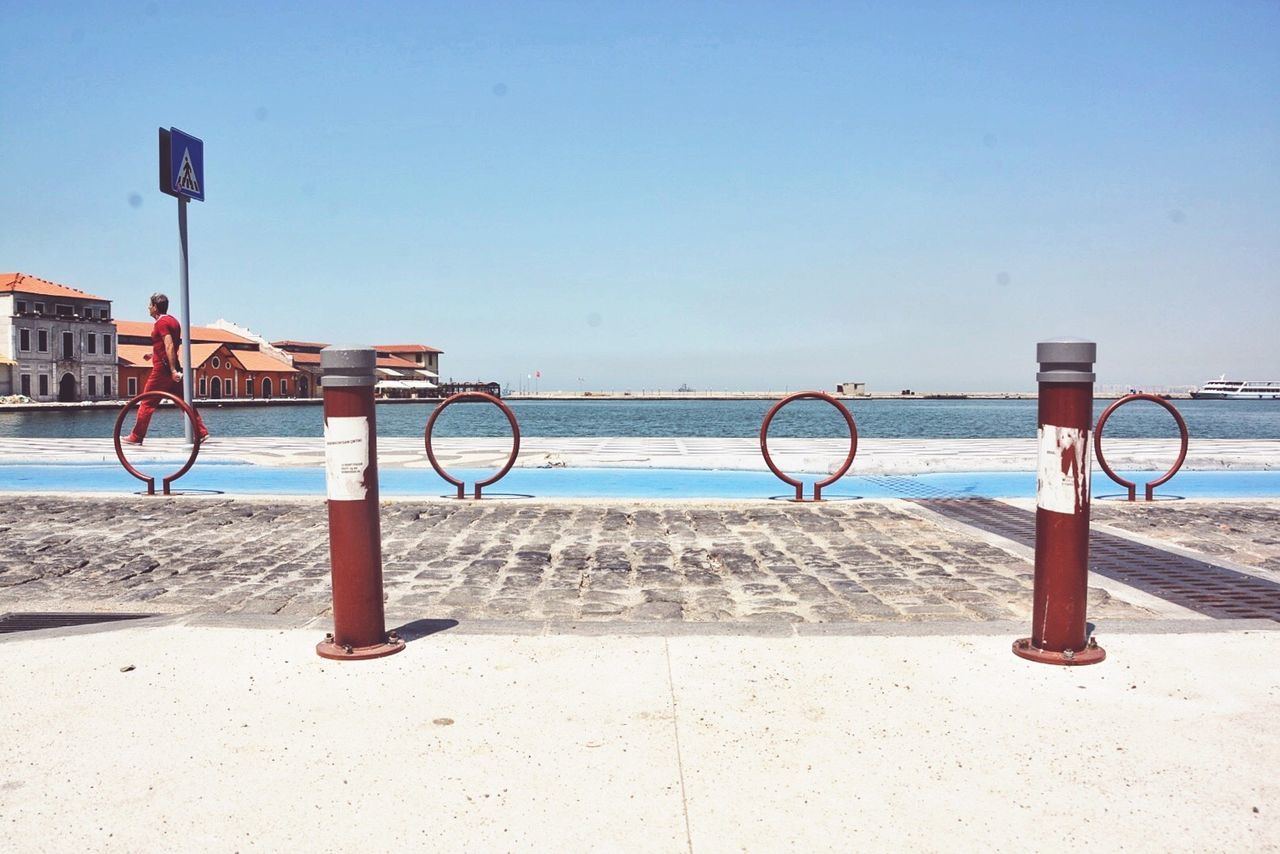 Bollard on sidewalk by sea against sky