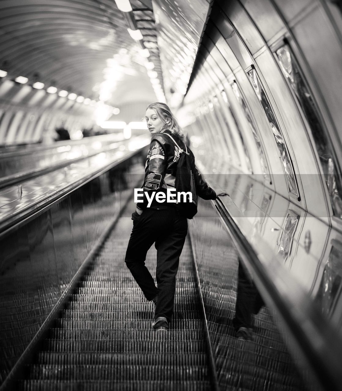 Full length portrait of woman standing on moving walkway