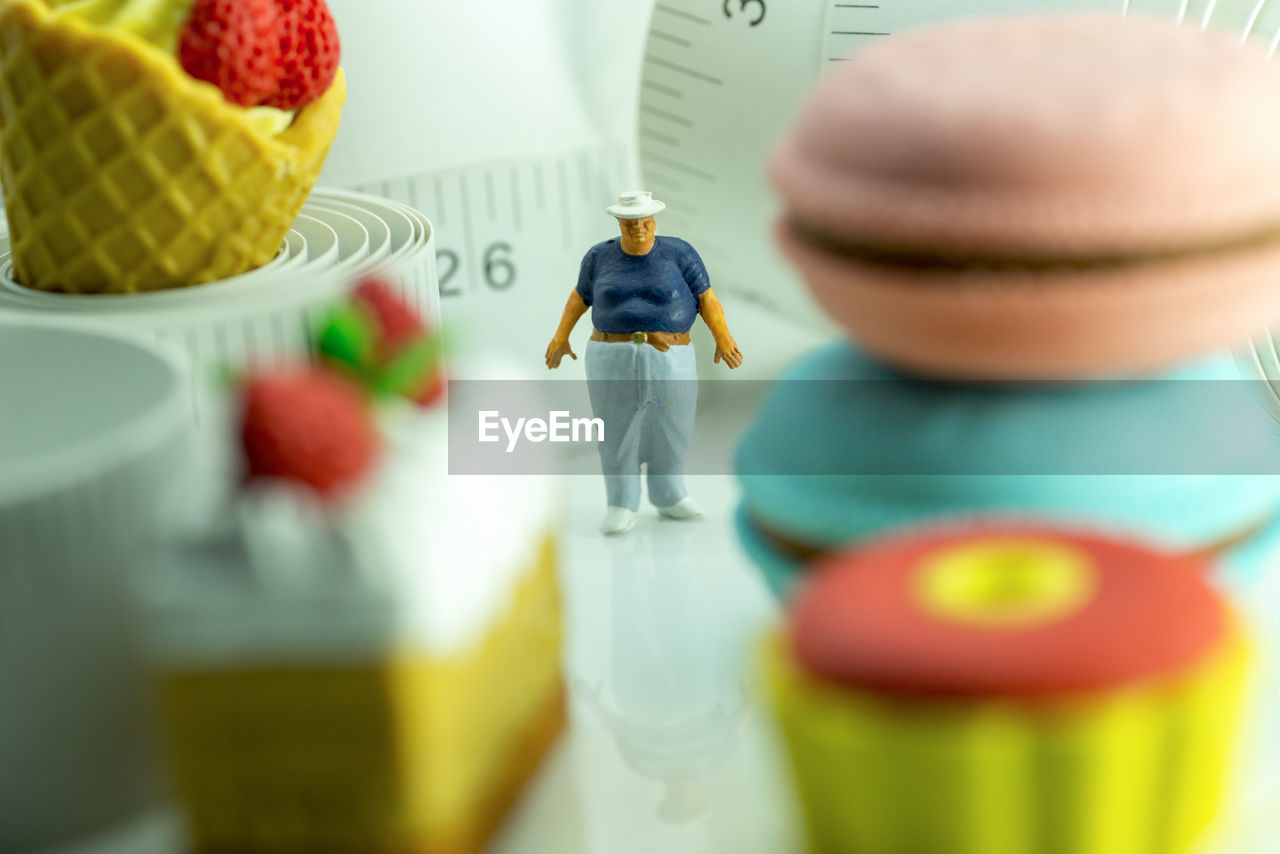 An overweight man with measuring tape and unhealthy food.
