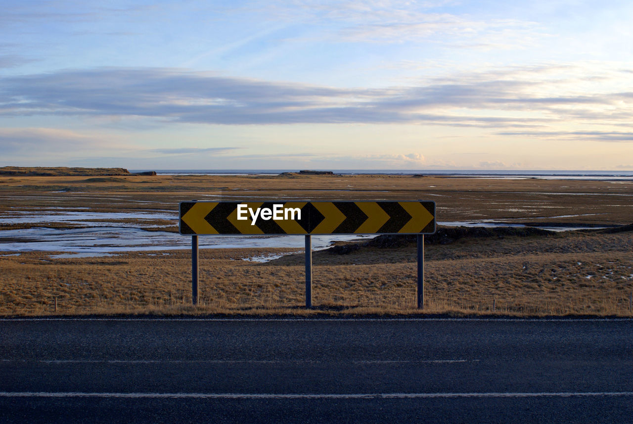 INFORMATION SIGN ON ROAD BY SEA AGAINST SKY