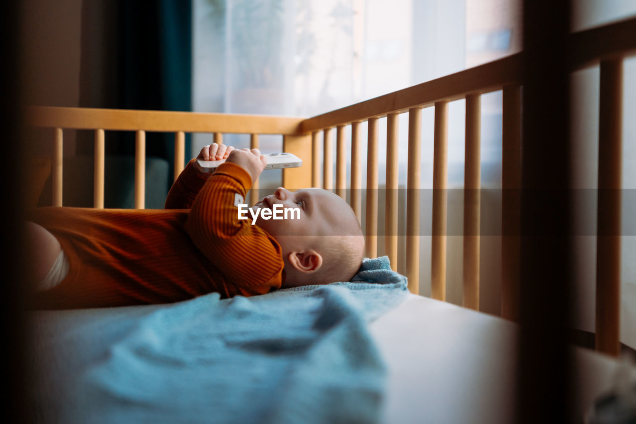 Cute boy holding mobile in crib