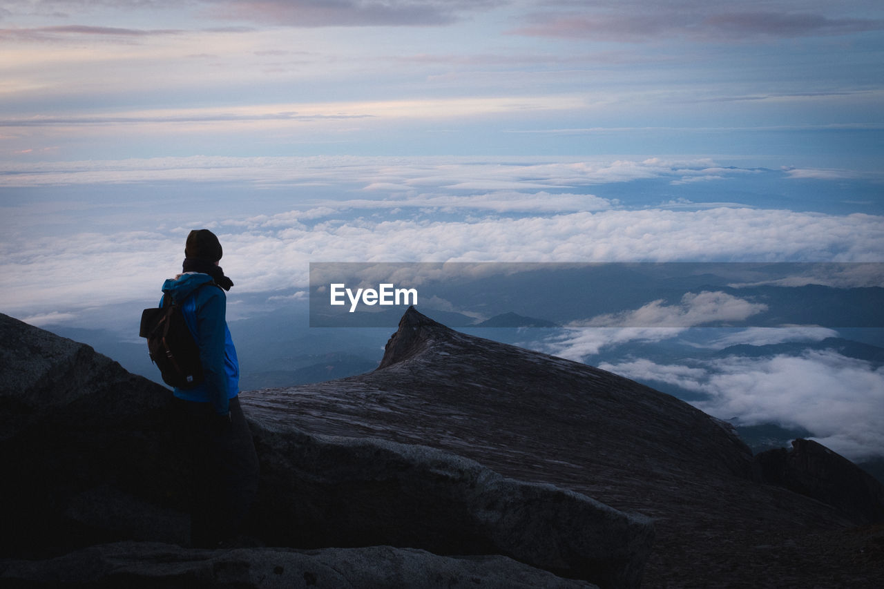 Rear view of man standing on mountain against sky