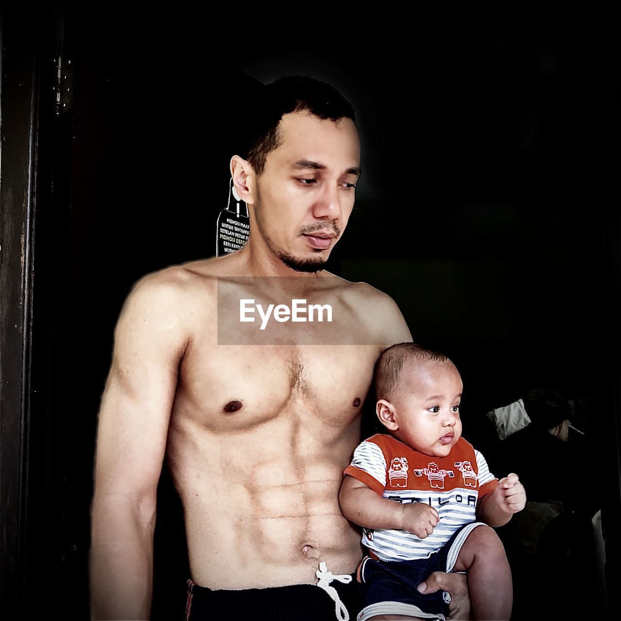 PORTRAIT OF SHIRTLESS MAN WITH BABY