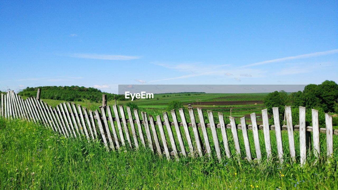 Fence on land against blue sky