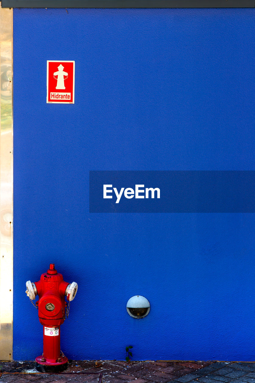 Red fire hydrant against blue wall