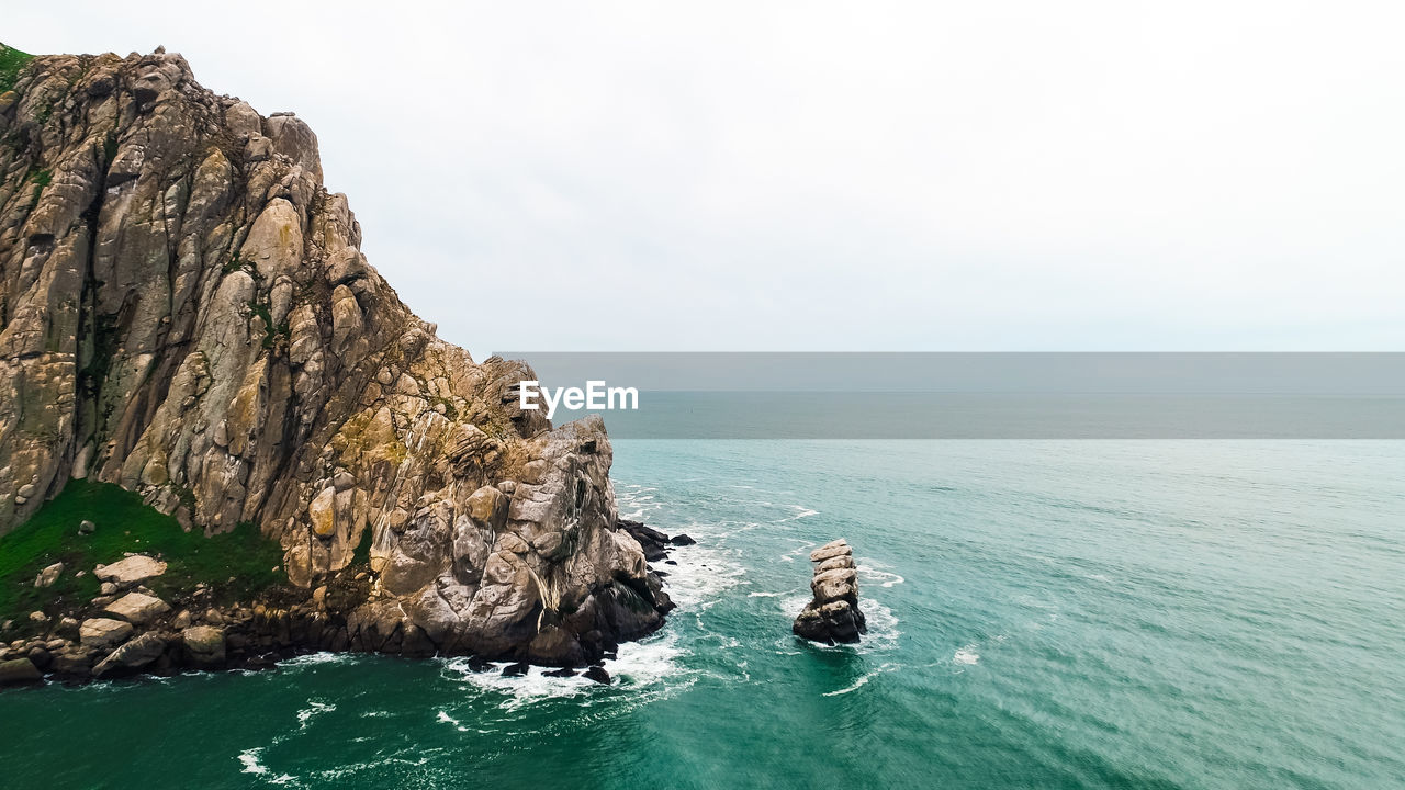 SCENIC VIEW OF ROCK FORMATIONS IN SEA AGAINST SKY