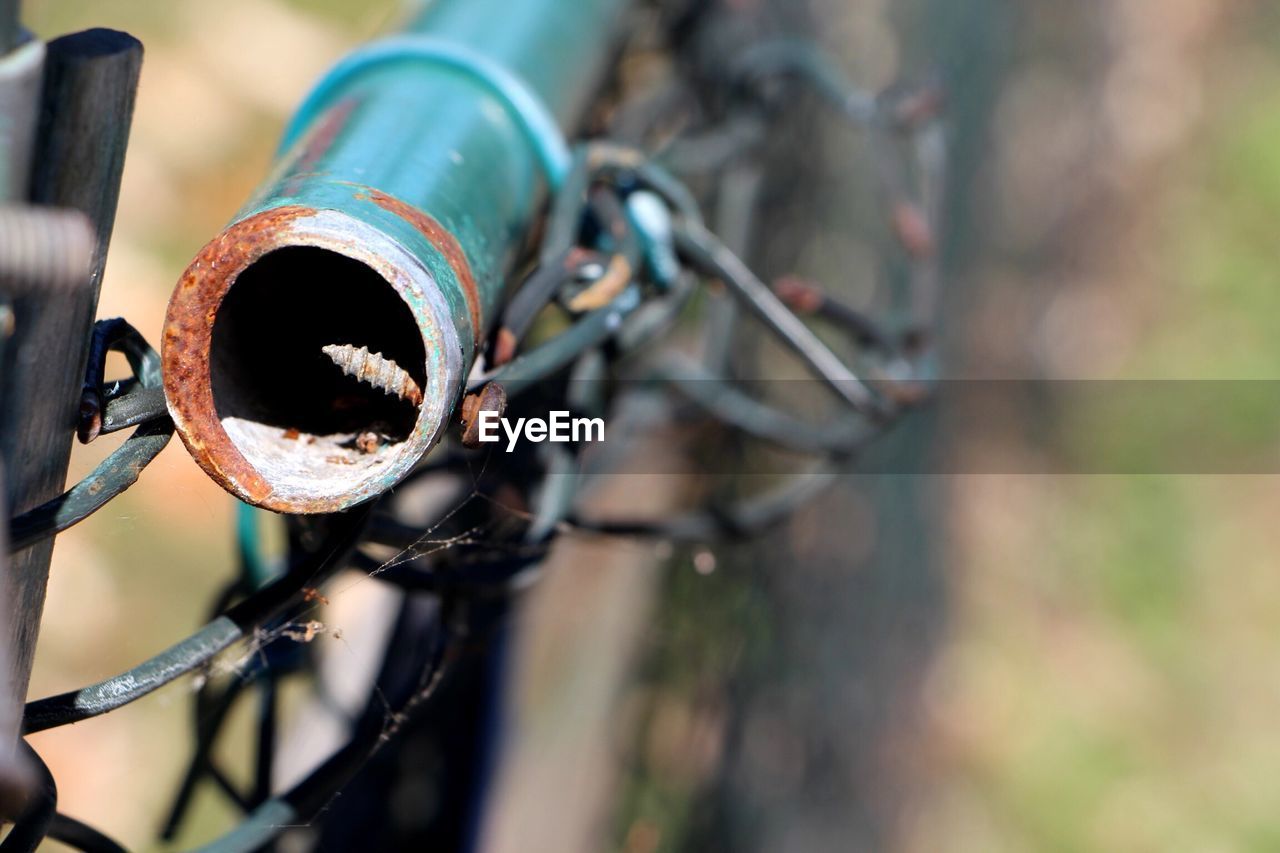 Close-up of pipe attached on chainlink fence