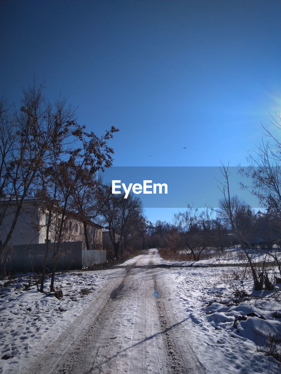 SNOW COVERED ROAD AGAINST CLEAR BLUE SKY