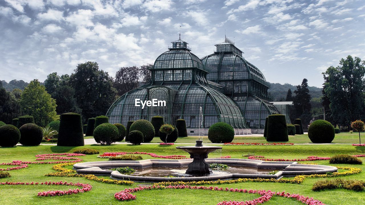 Modern built structures in park against cloudy sky