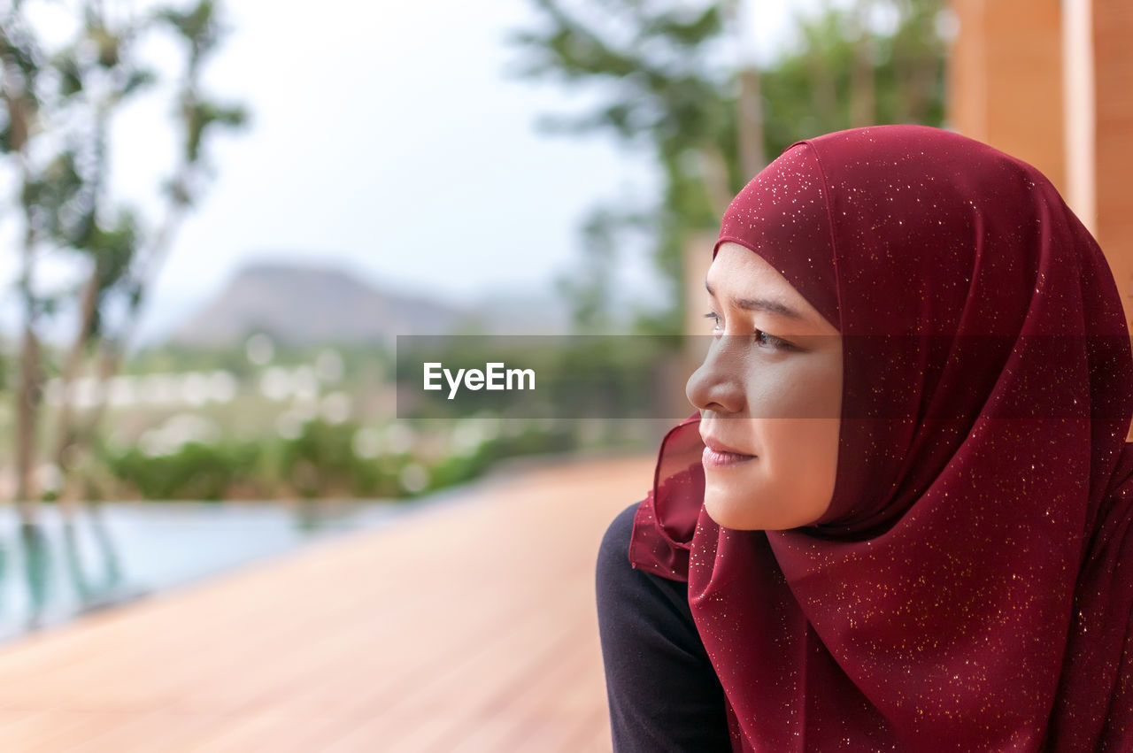Woman in red hijab looking away outdoors