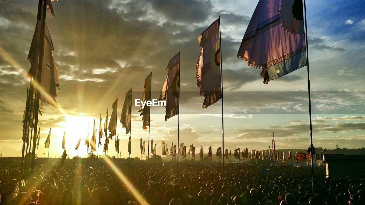 People with flags against sky during sunset