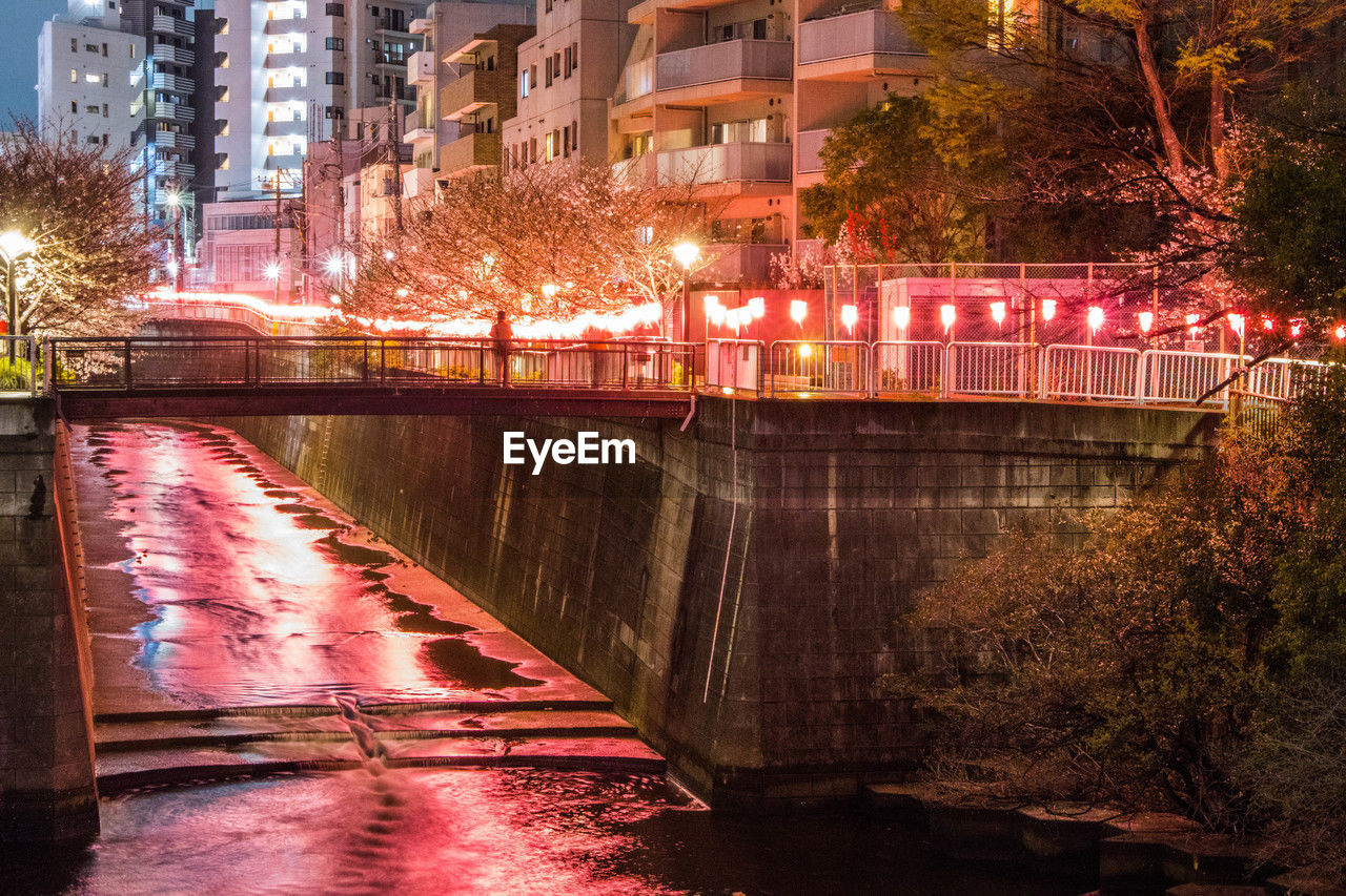 architecture, built structure, illuminated, building exterior, city, night, evening, reflection, water, urban area, cityscape, waterway, tree, nature, street, building, plant, transportation, no people, travel destinations, river, outdoors, city life, motion, light, bridge, dusk, lighting equipment, downtown, residential district, street light