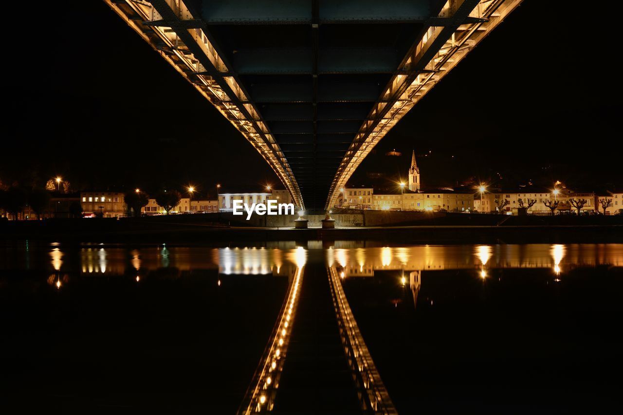 Illuminated bridge over river at night