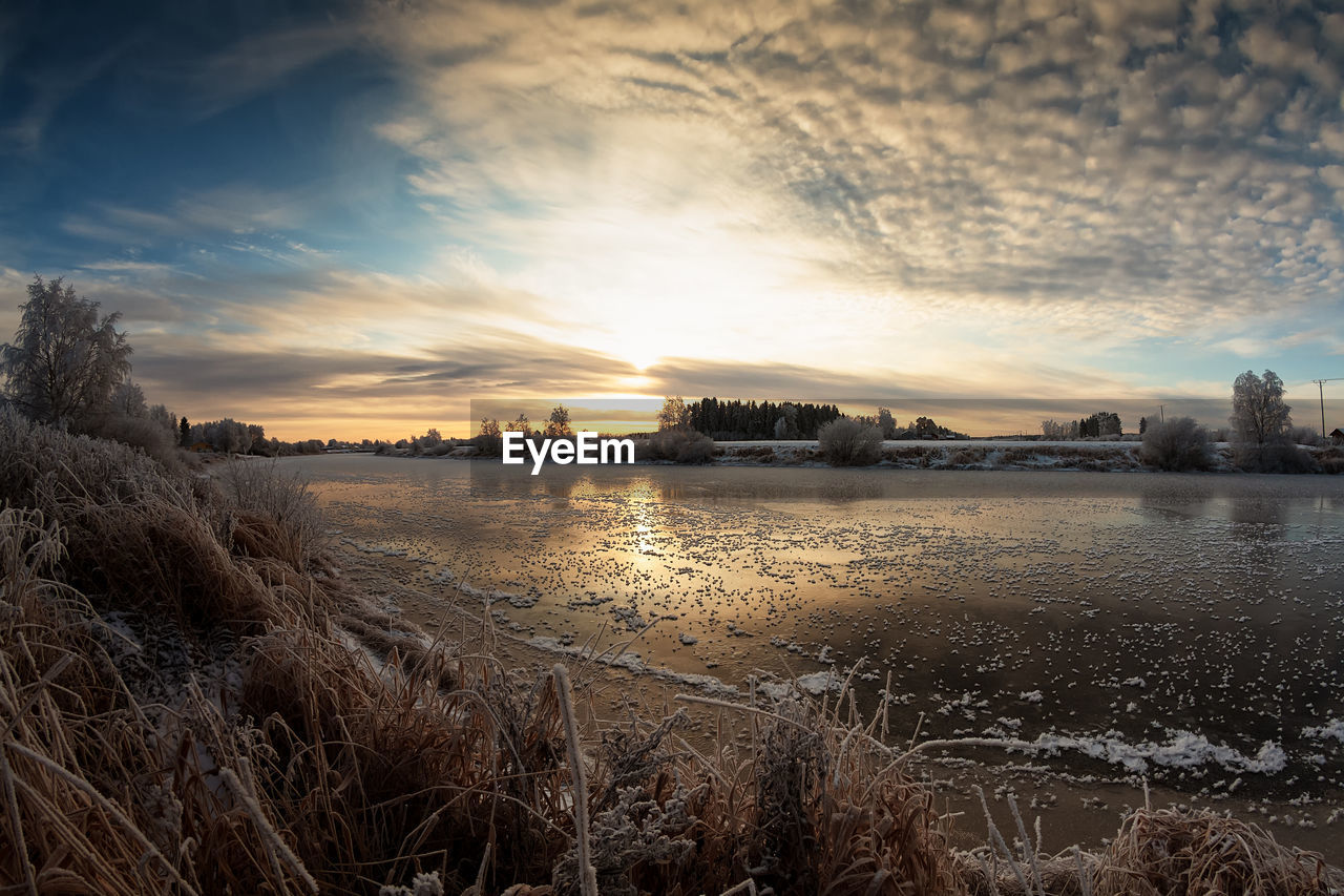 The sun rises over the rive on a cold morning at finland. the river water is slowly freezing.