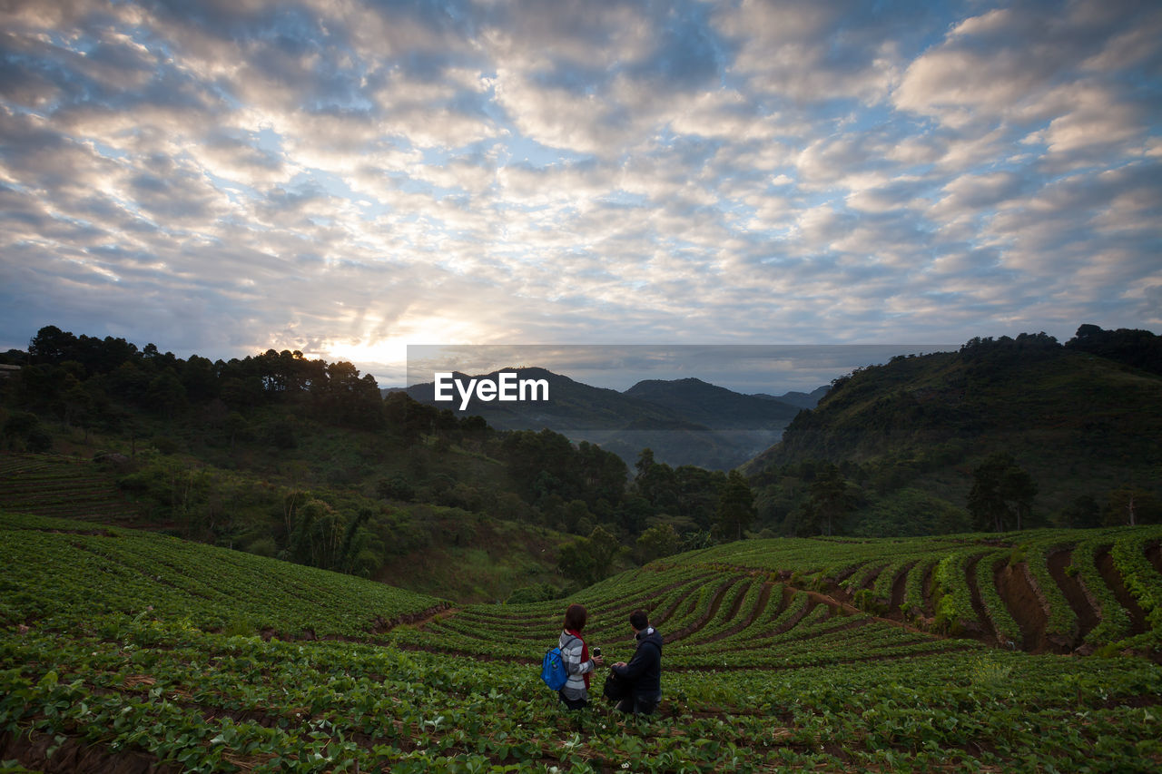 People in farm against cloudy sky