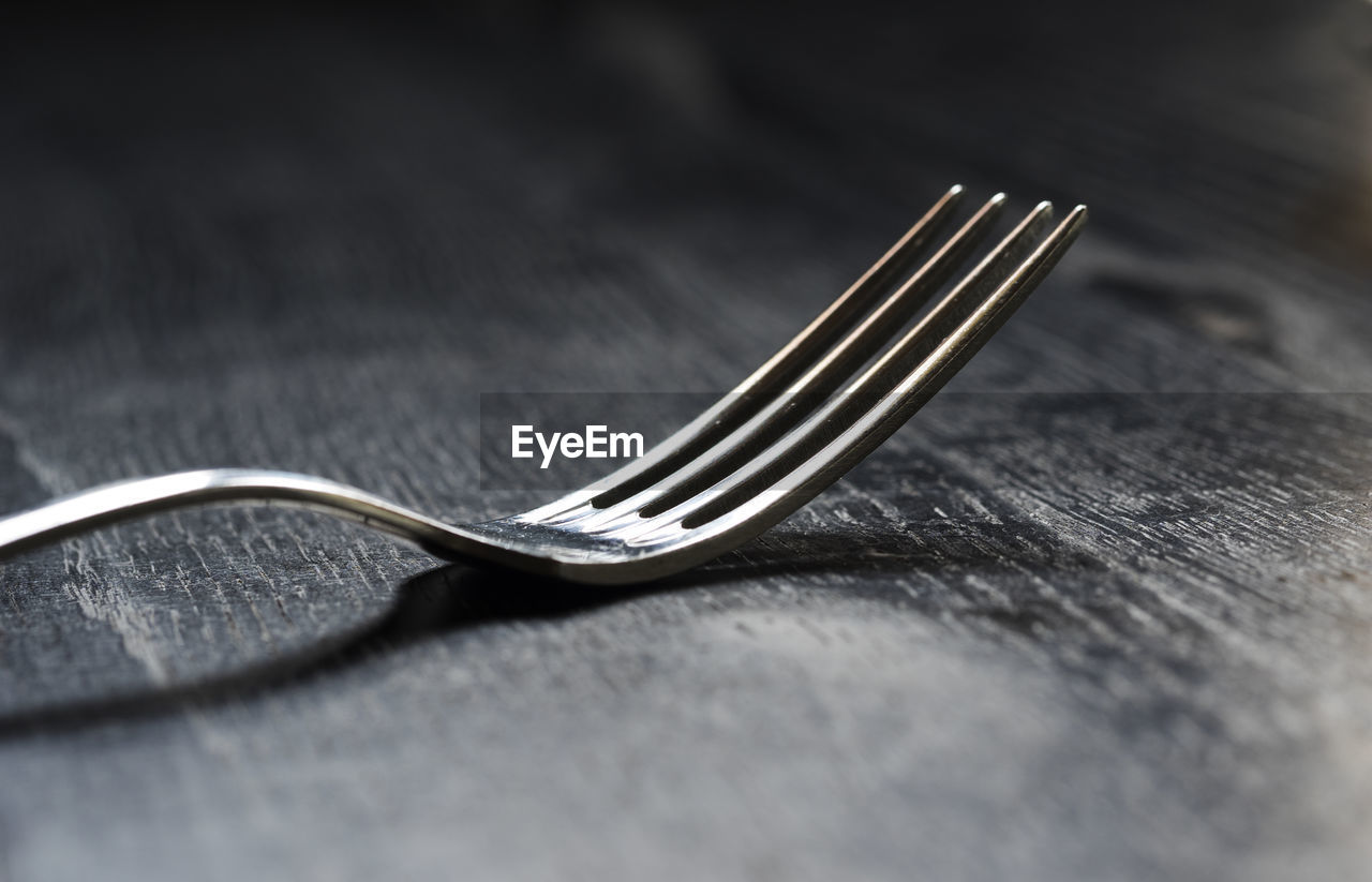 Close-up of metal fork on wooden table