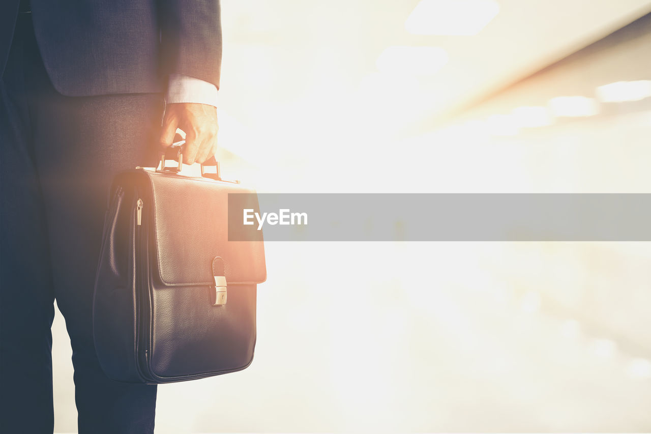 Midsection of businessman holding briefcase