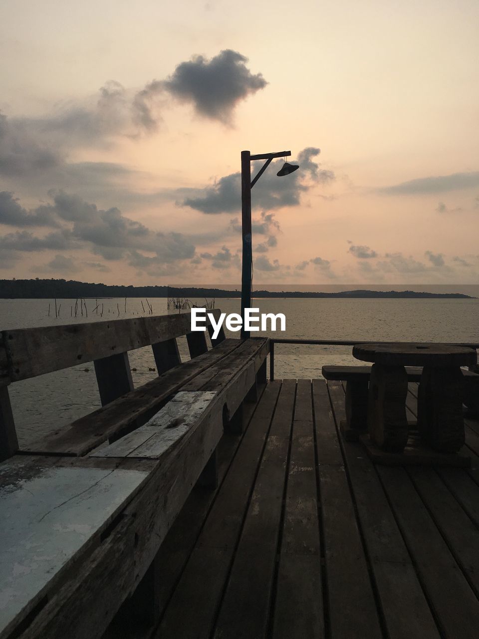 Wooden bench on deck against sea