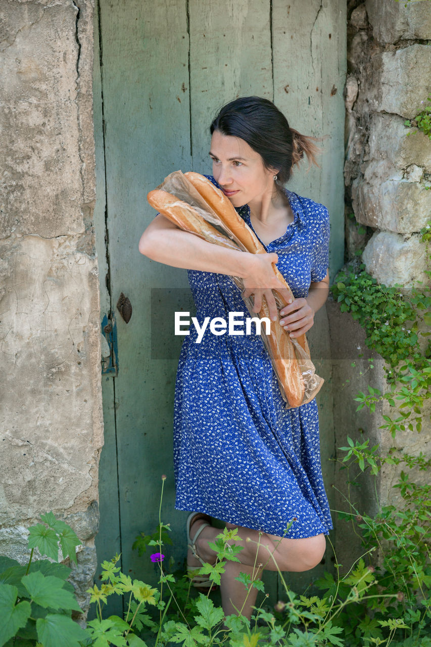 Young woman standing with french baguettes in the countryside