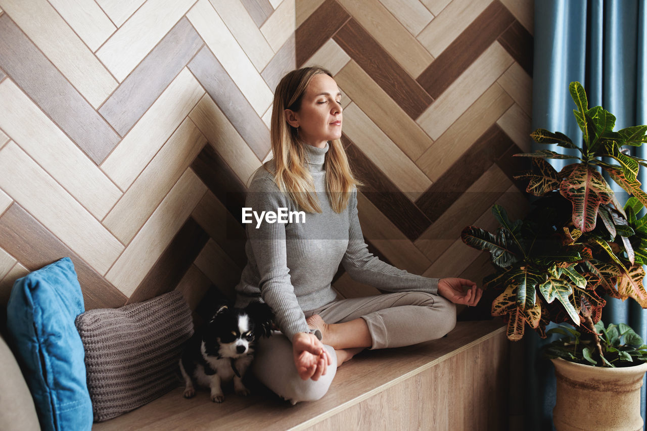 A young woman sits in the lotus position and meditates.