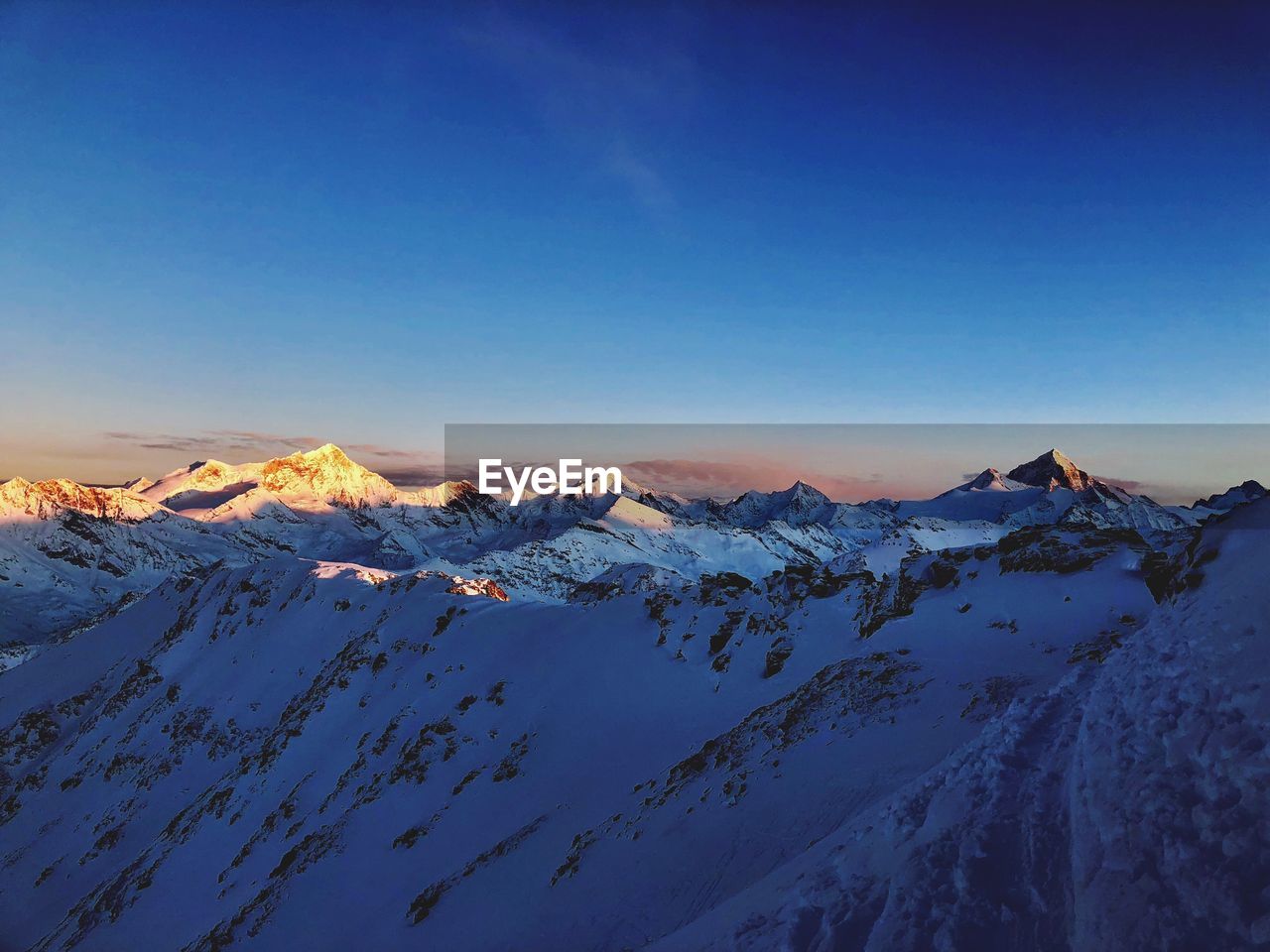 Scenic view of snowcapped mountains against clear blue sky