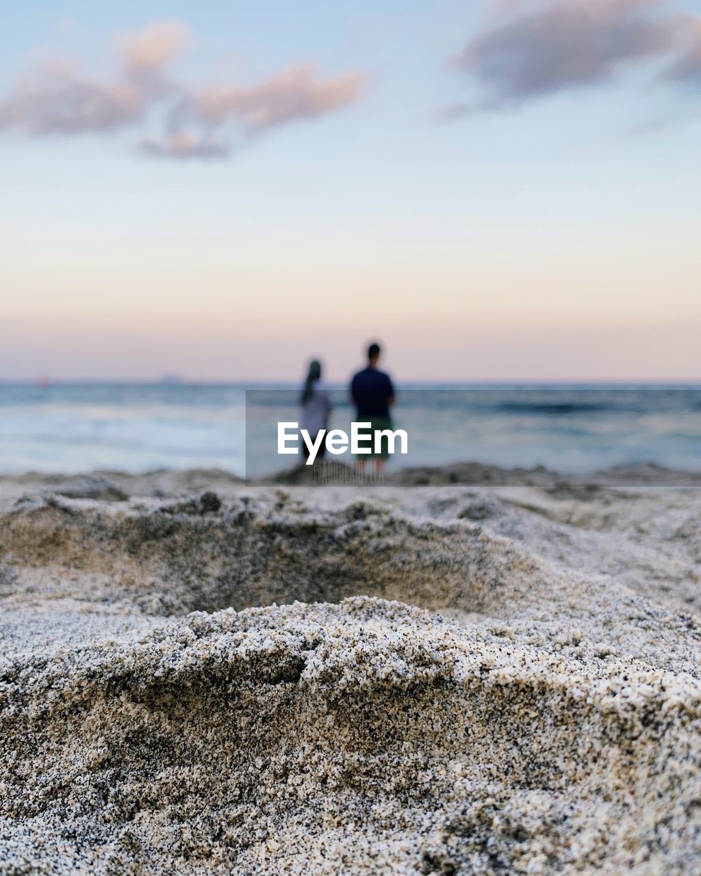 Couple at beach against sky during sunset